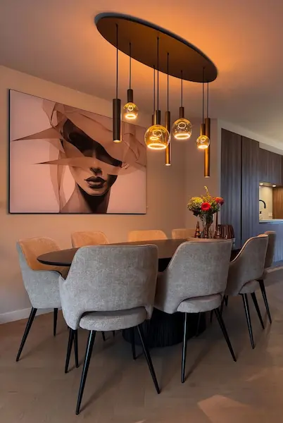 Salle à manger contemporaine avec luminaire design suspendu et fauteuils tissu — rénovation Diamond Agencement